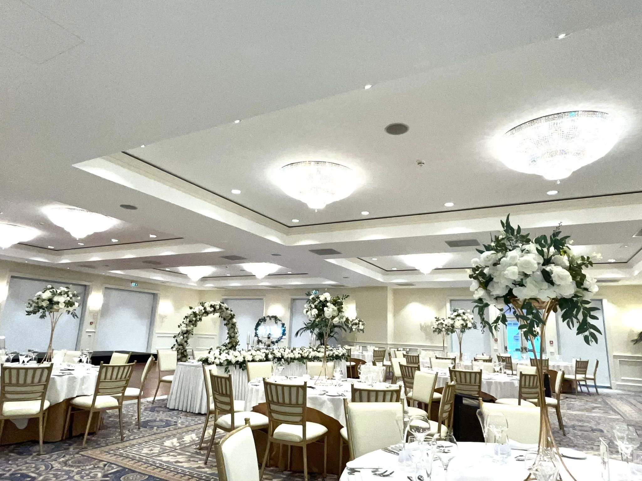 Dining hall with tables set for a formal event, decorated with floral arrangements.